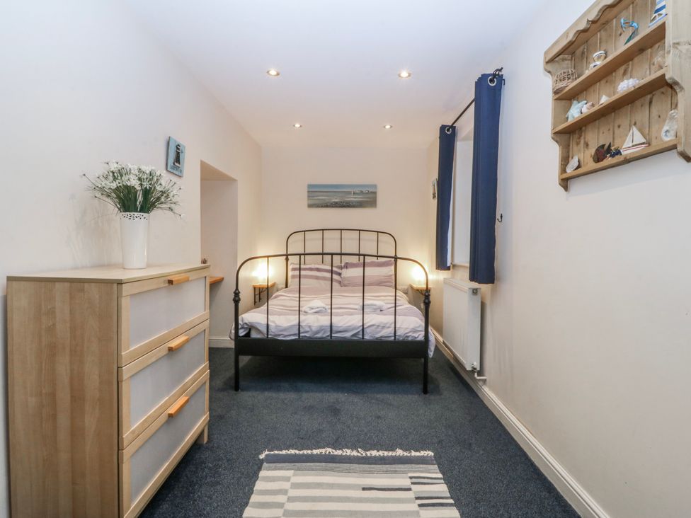 A bedroom with a bed and dresser at Bwthyn Llechen in Porthmadog