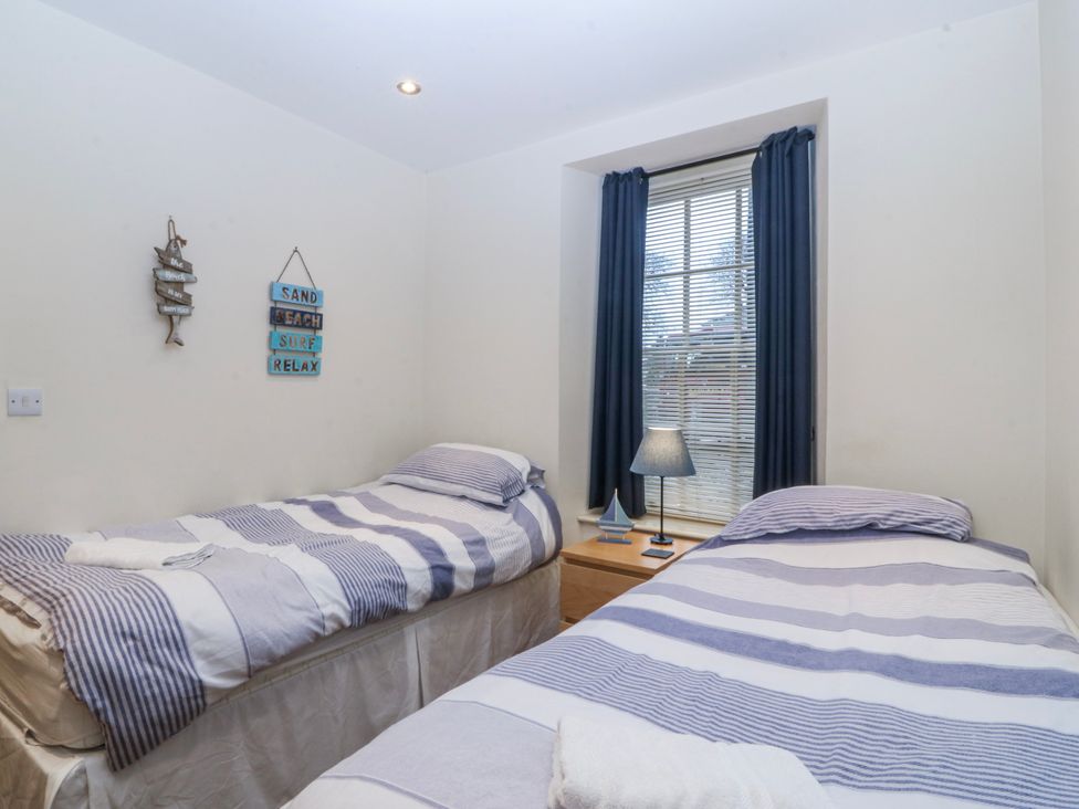 A bedroom with two single beds and a window at Bwthyn Llechen in Porthmadog