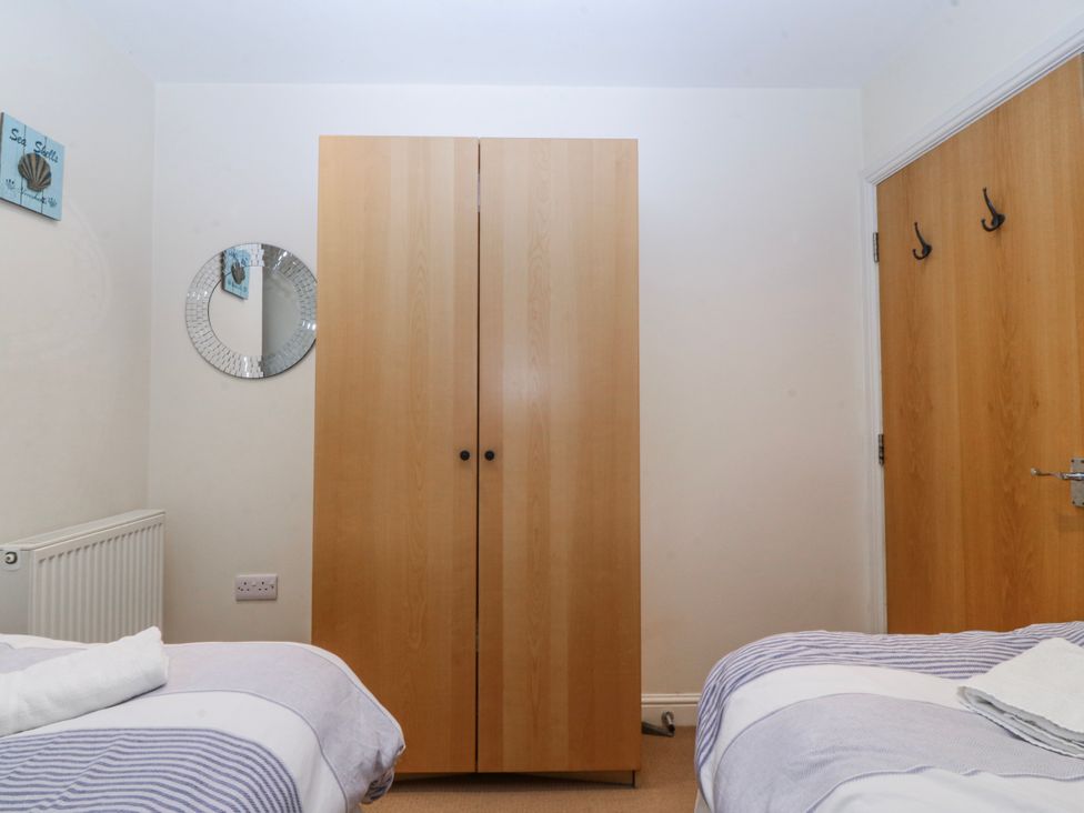 A bedroom featuring a wardrobe, mirror, bed, and hooks at Bwthyn Llechen in Porthmadog