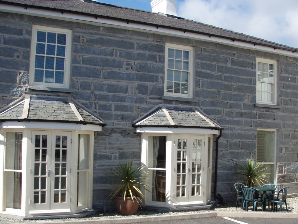 A house exterior with stone walls and patio furniture at Bwthyn Llechen in Porthmadog