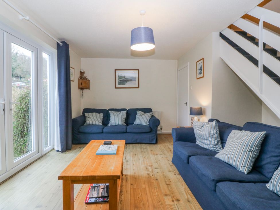 A living room with blue sofas and a wooden coffee table at Bwthyn y Mor in Borth-y-Gest near Porthmadog