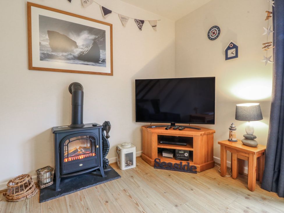 A living room with a stove and television at Bwthyn y Mor in Borth-y-Gest near Porthmadog