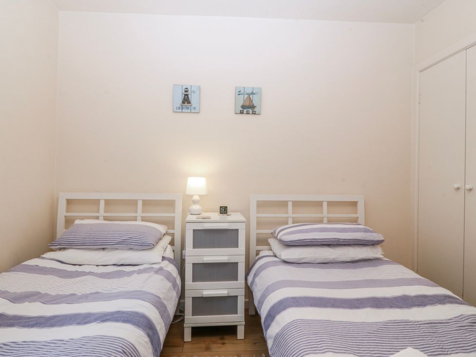 A bedroom with twin beds and a nightstand at Bwthyn y Mor Borth-y-Gest near Porthmadog
