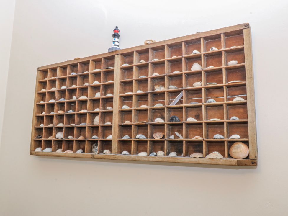 A wooden display case filled with shells and a lighthouse figurine at Bwthyn y Mor in Borth-y-Gest near Porthmadog