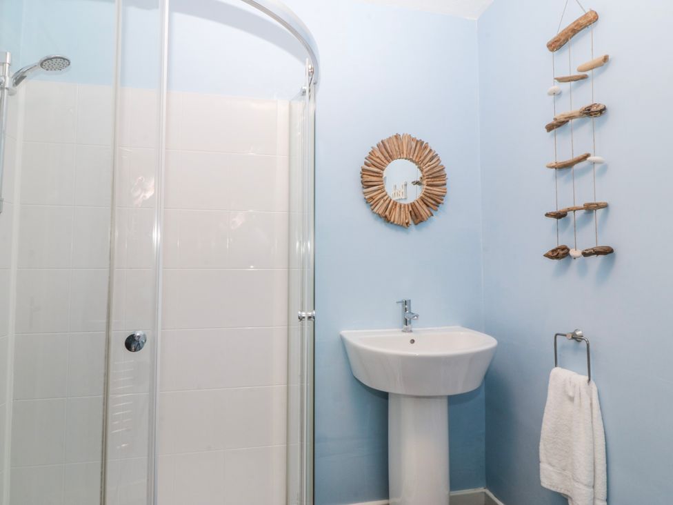 A bathroom with a shower, sink, and mirror at Bwthyn y Mor in Borth-y-Gest near Porthmadog