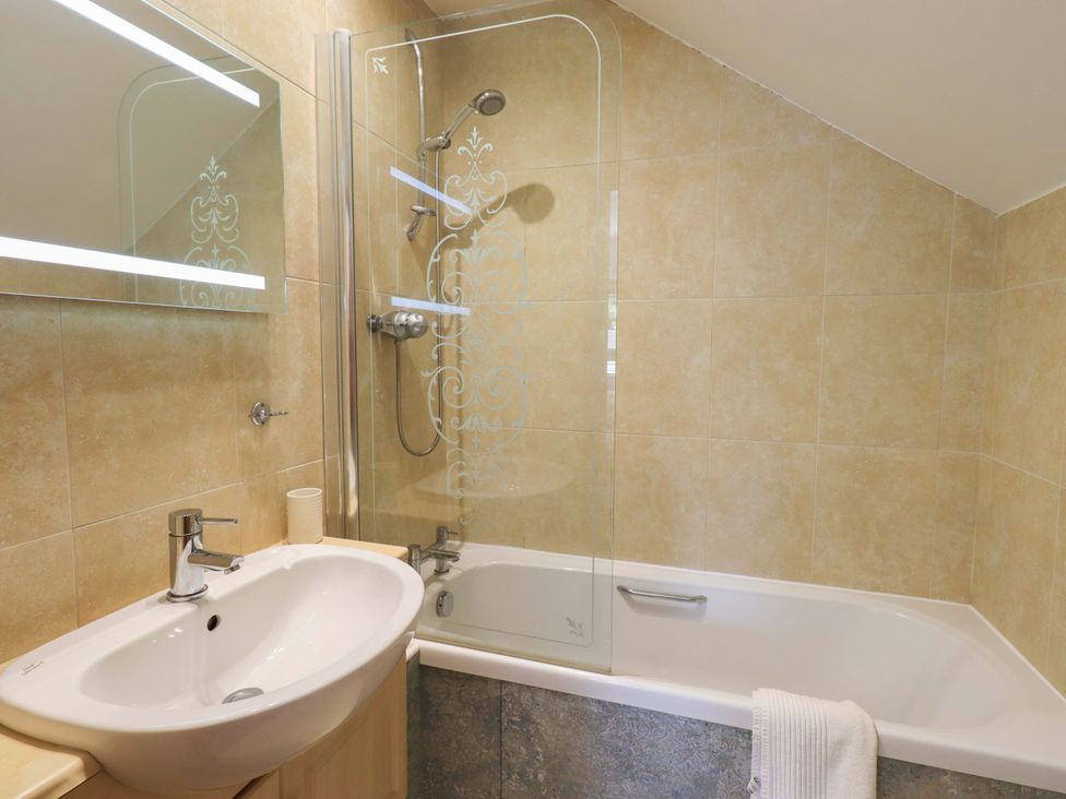 A bathroom with a bathtub and shower at Lakeside Cottage in Ecclerigg near Ambleside