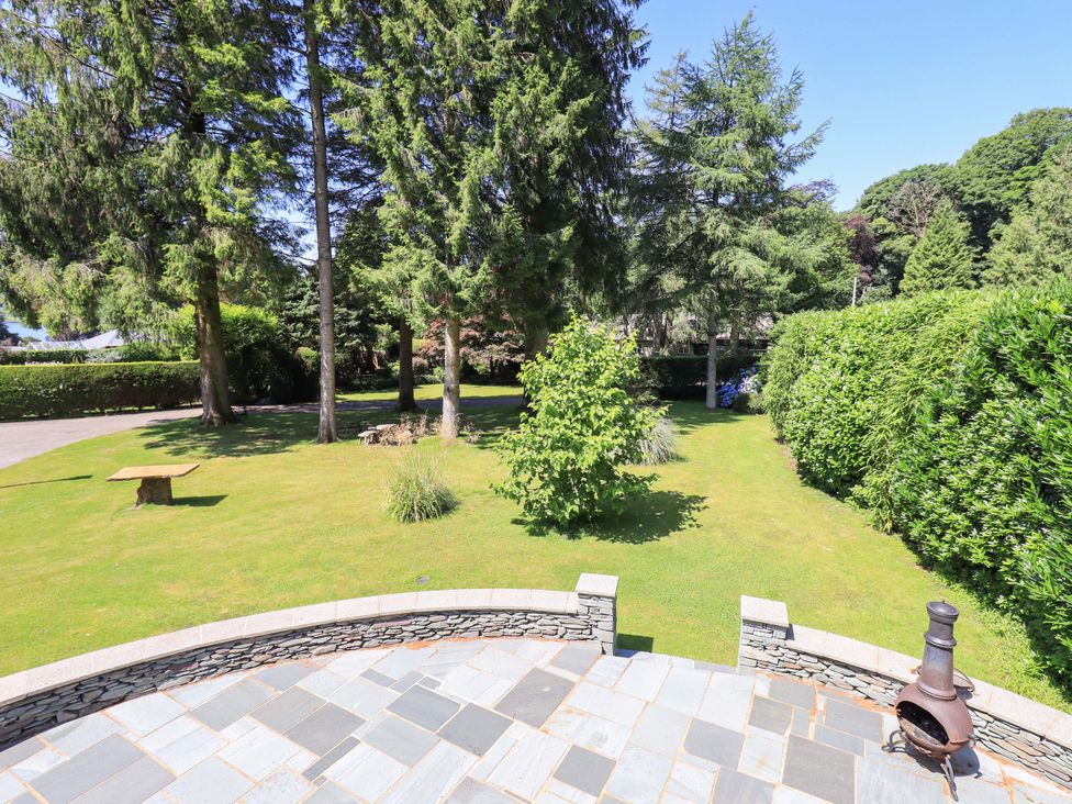 A garden with trees and a stone patio at Waterhead Cottage, Ecclerigg, near Troutbeck Bridge