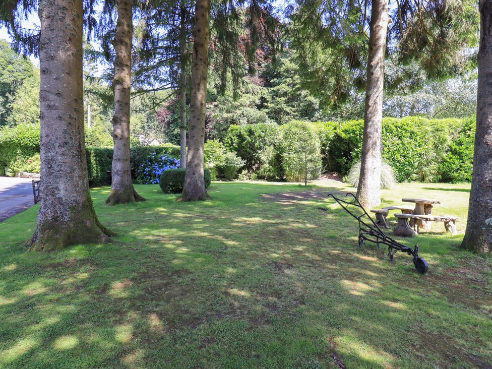 A garden with trees, a bench, and a table at Waterhead Cottage, Ecclerigg, near Troutbeck Bridge