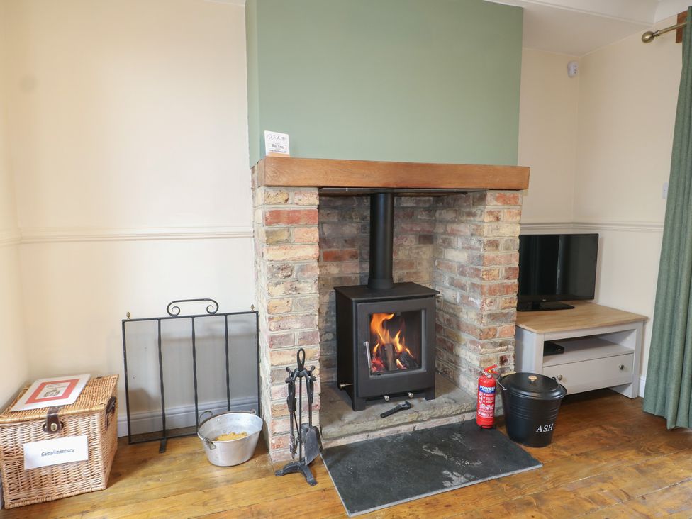 A living room with a wood stove and television at Bay Cosy in Pevensey Bay