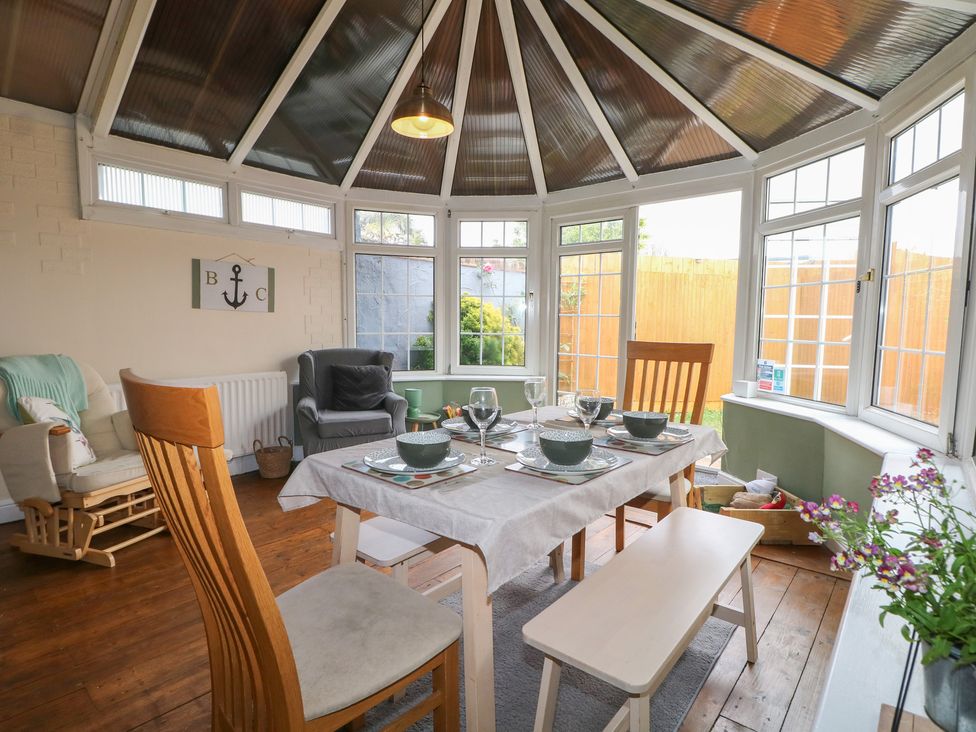 A conservatory with a dining table and chairs at Bay Cosy in Pevensey Bay