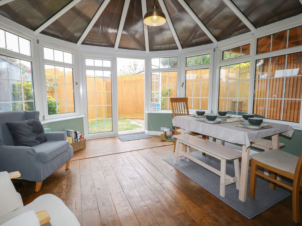 A conservatory with a dining table and chairs at Bay Cosy in Pevensey Bay