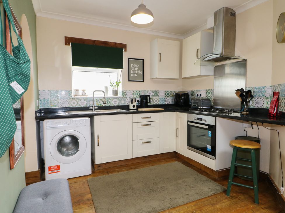 A kitchen with a washing machine and appliances at Bay Cosy in Pevensey Bay
