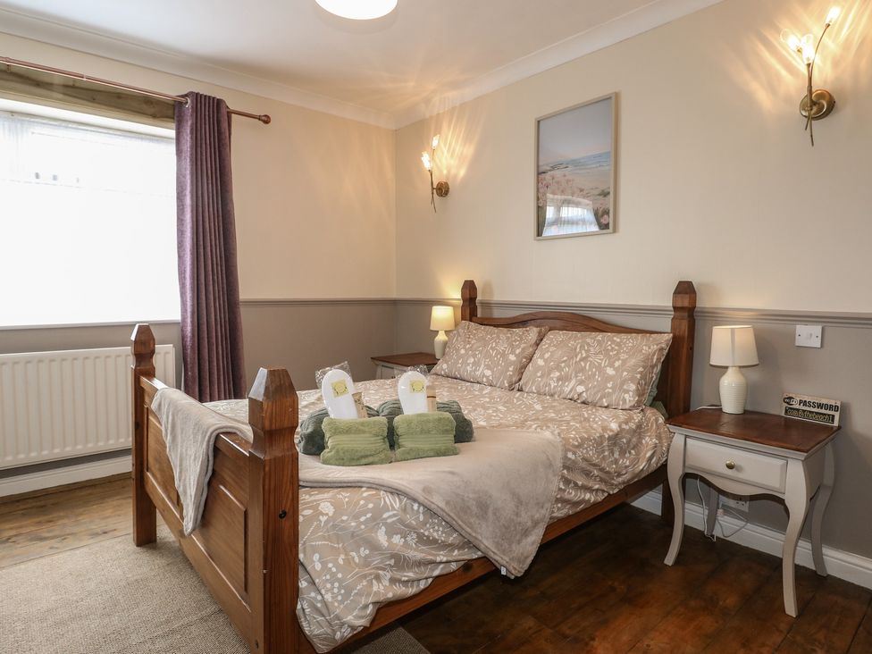 A bedroom with a wooden bed and nightstand at Bay Cosy in Pevensey Bay