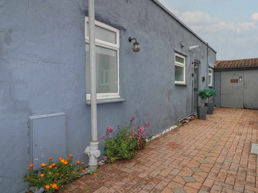 An outdoor area with a brick pathway and flowering plants at Bay Cosy in Pevensey Bay