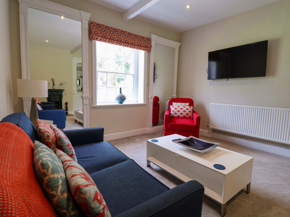 A living room with a sofa, coffee table, and television at South Tower Cottage in Capesthorne near Macclesfield