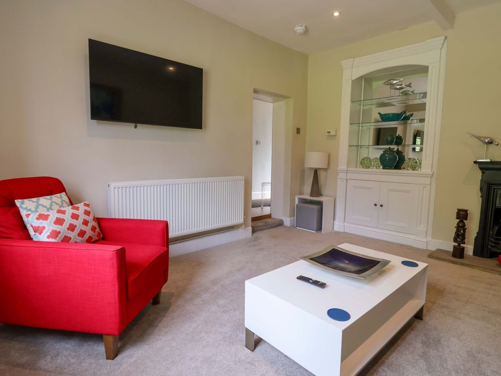 A living room with a red armchair and television at South Tower Cottage Capesthorne near Macclesfield