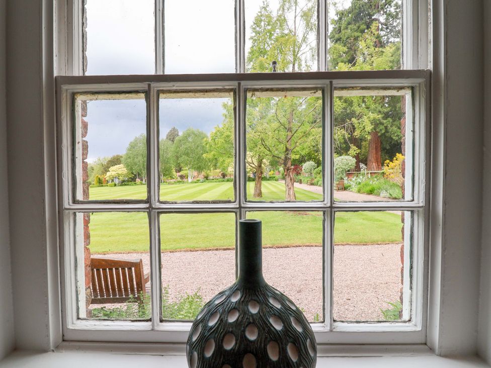 A window view showing a garden with a bench at South Tower Cottage in Capesthorne near Macclesfield