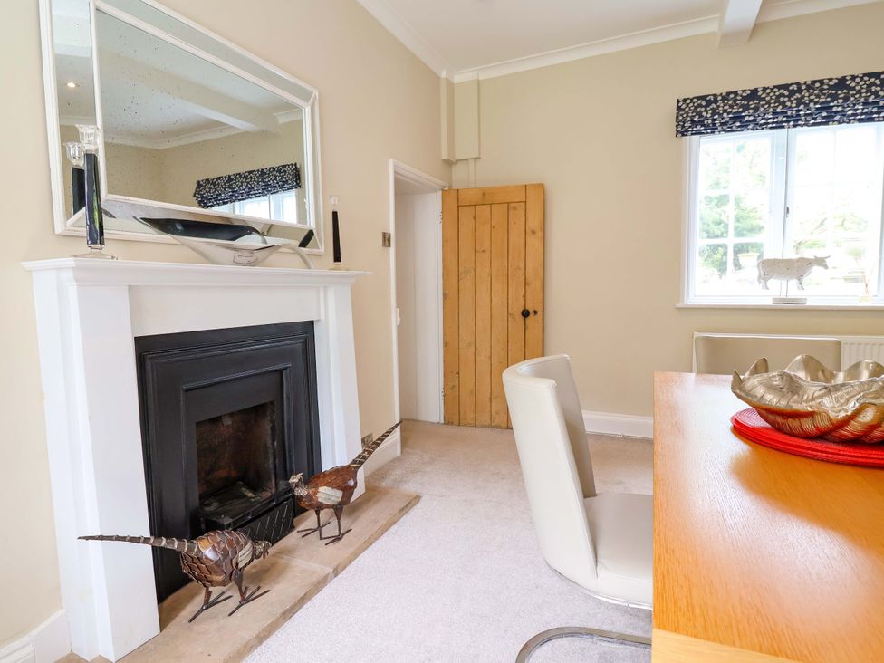 A dining room with fireplace and wooden door at South Tower Cottage in Capesthorne near Macclesfield
