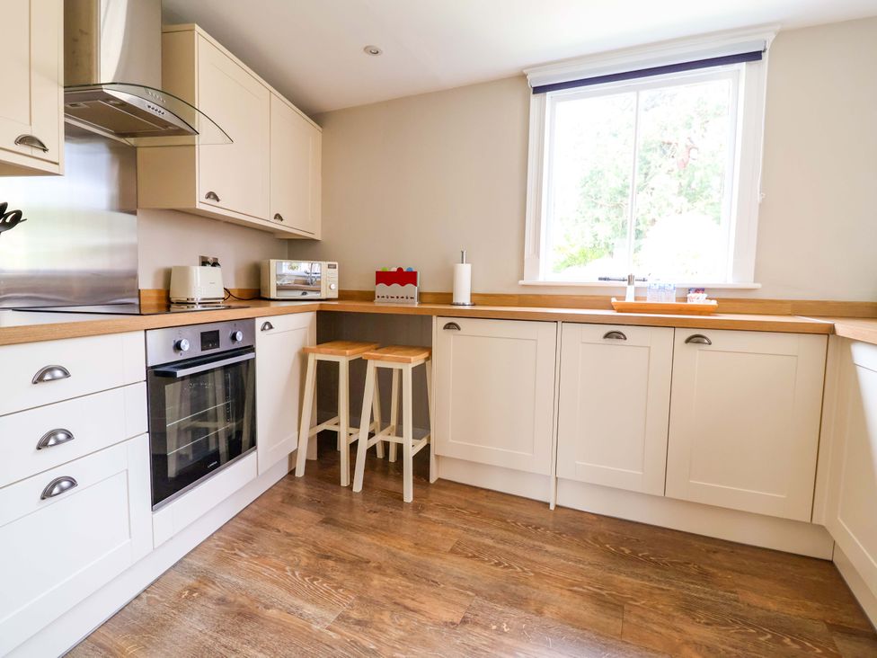 A kitchen with cabinets, appliances and stools at South Tower Cottage in Capesthorne near Macclesfield
