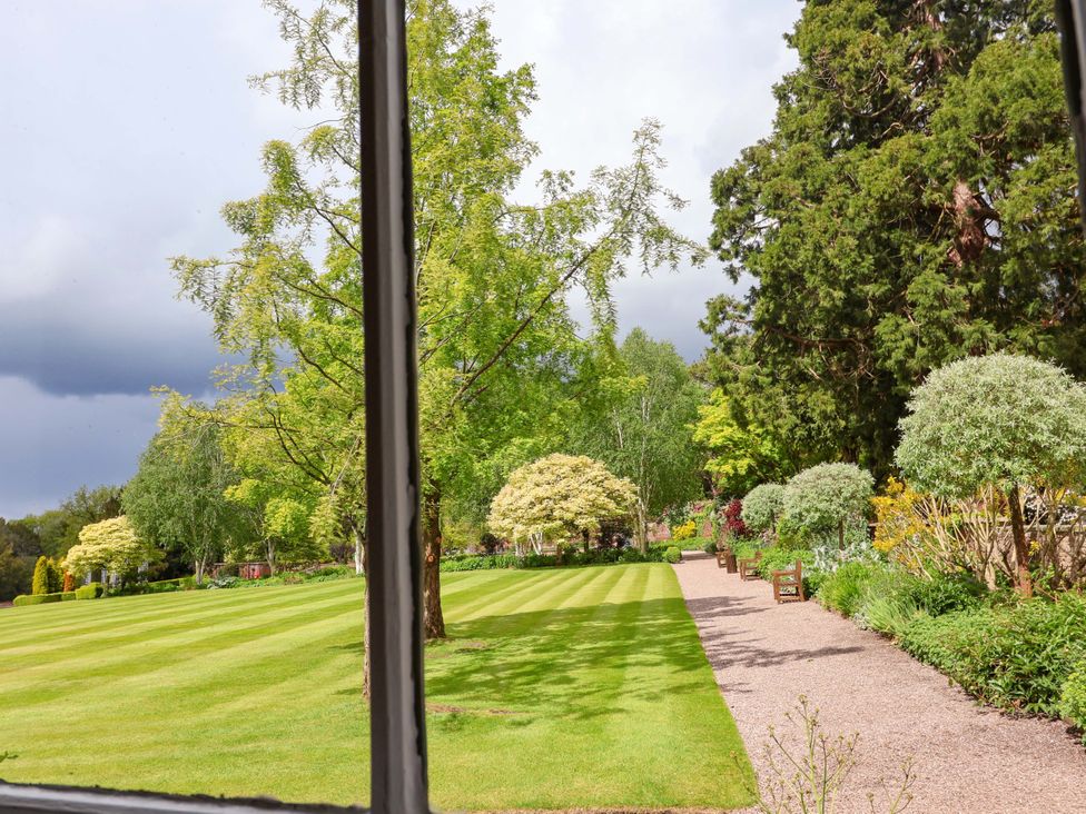 A garden view with trees and a pathway at South Tower Cottage Capesthorne near Macclesfield