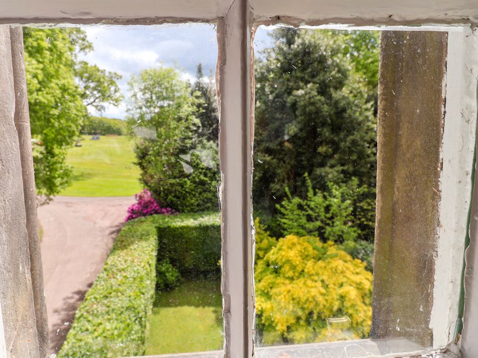 A view from a window showing greenery and a pathway at South Tower Cottage Capesthorne near Macclesfield