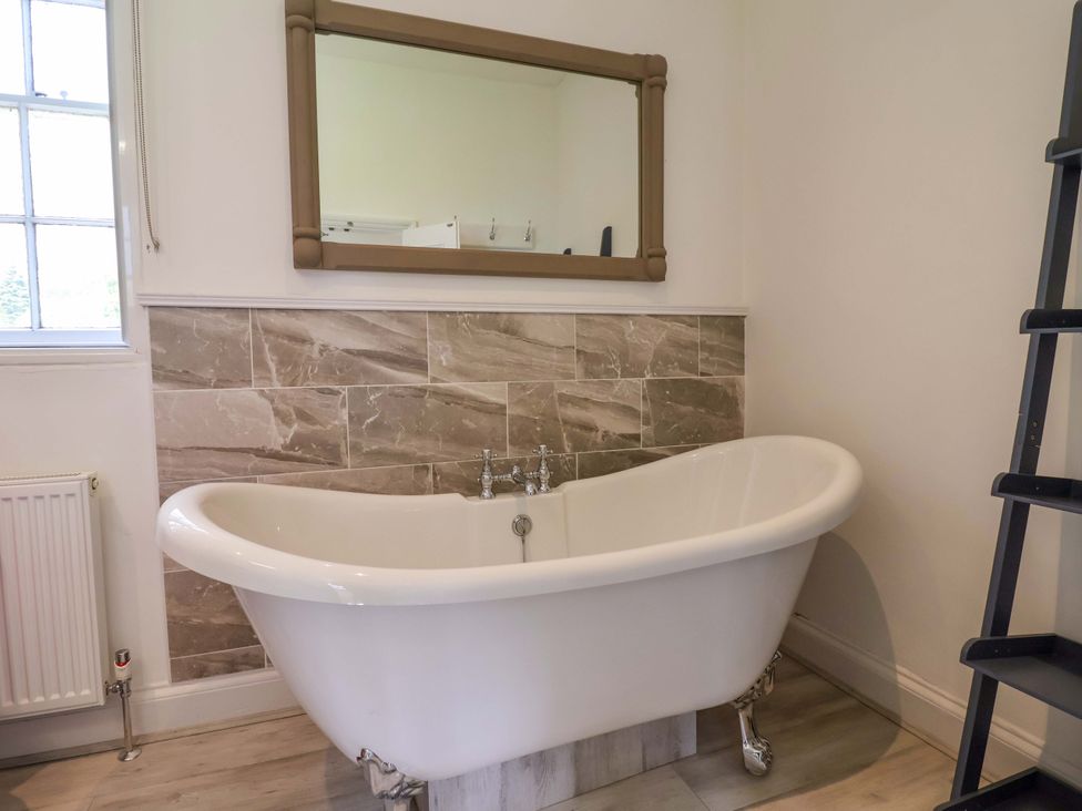 A bathroom with a freestanding bathtub and a large mirror at South Tower Cottage in Capesthorne near Macclesfield