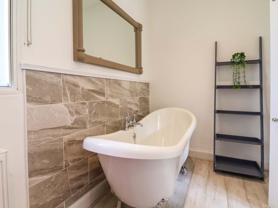 A bathroom with a bathtub and shelf at South Tower Cottage in Capesthorne near Macclesfield