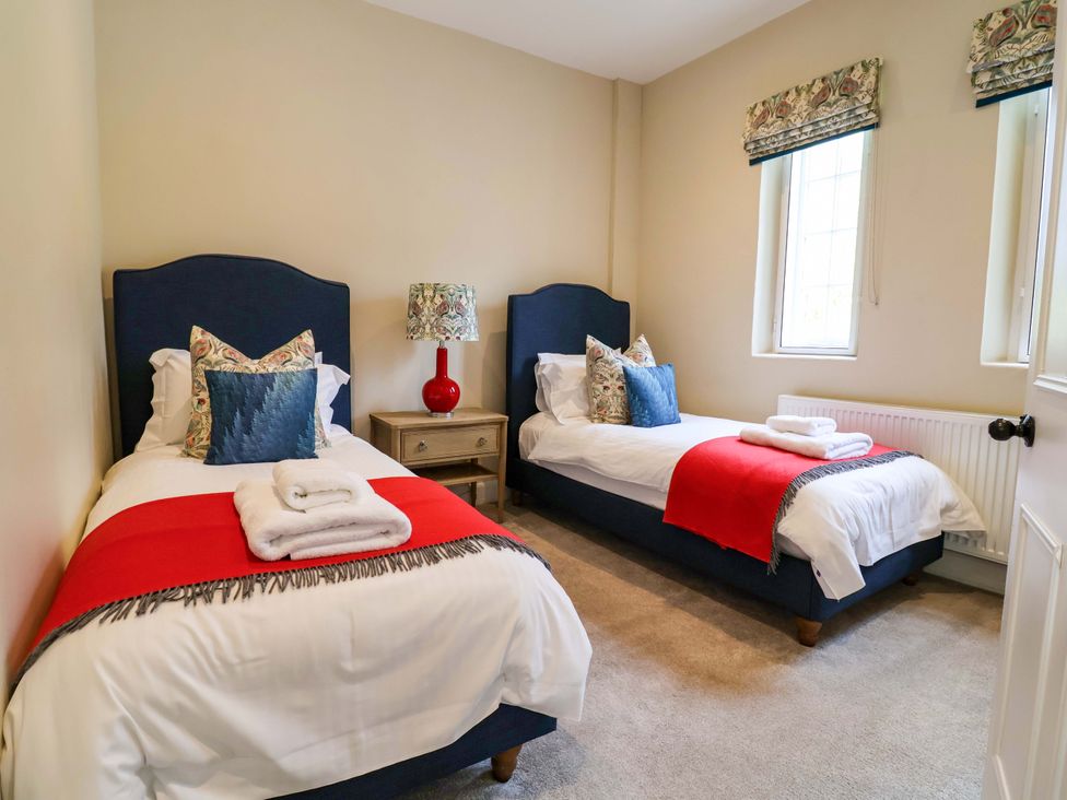 A bedroom with two single beds and a bedside table at South Tower Cottage in Capesthorne near Macclesfield
