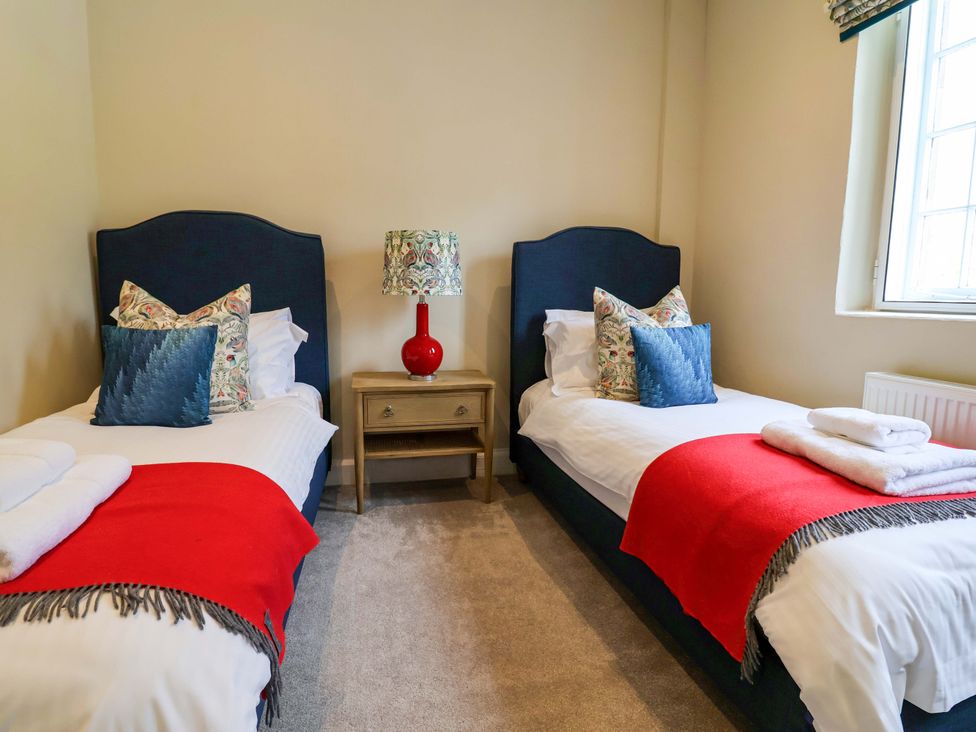 A bedroom with two twin beds and a bedside table at South Tower Cottage Capesthorne near Macclesfield