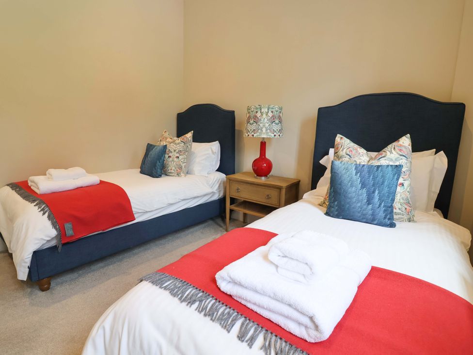 A bedroom with two beds and a side table at South Tower Cottage Capesthorne near Macclesfield