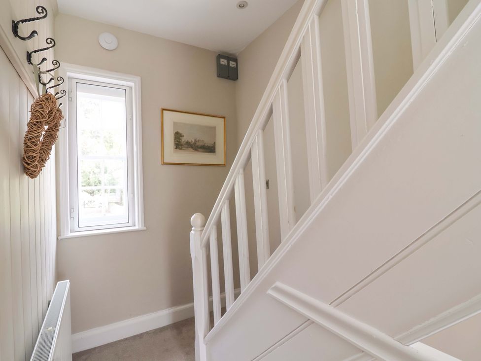 A hallway with a staircase and a window at South Tower Cottage Capesthorne near Macclesfield