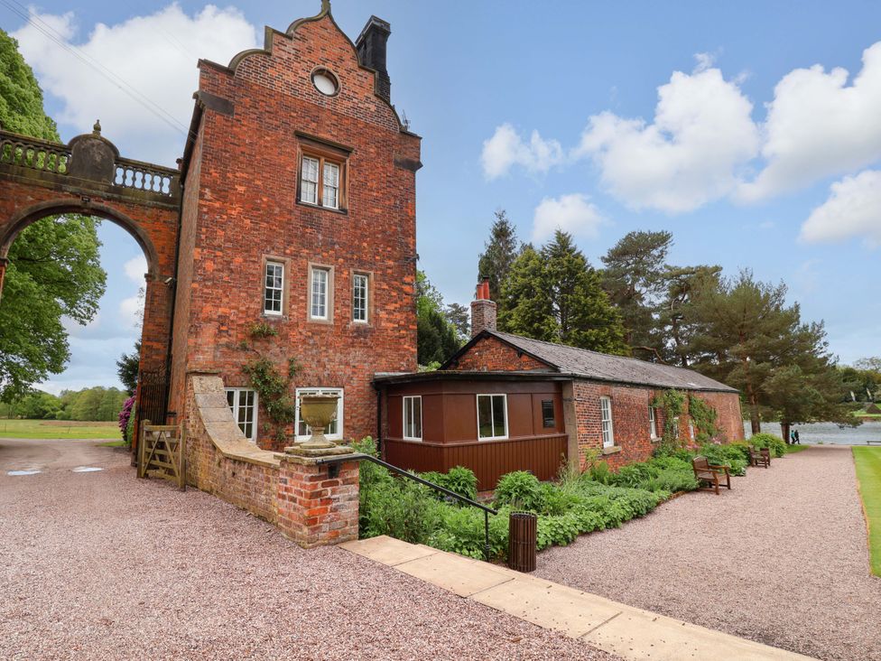 An outdoor view of a brick building with an archway and garden at South Tower Cottage in Capesthorne near Macclesfield