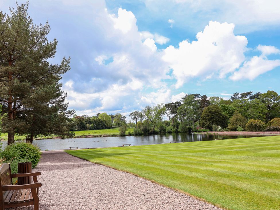 An outdoor area with a bench and a lake at South Tower Cottage Capesthorne near Macclesfield