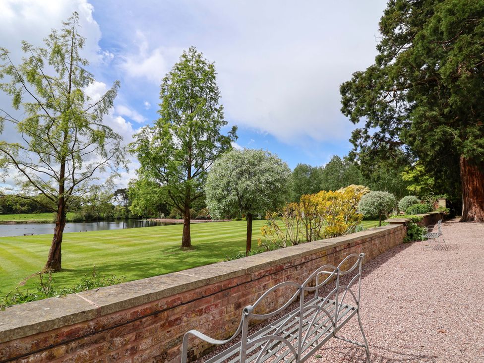A garden with benches overlooking water at South Tower Cottage in Capesthorne near Macclesfield