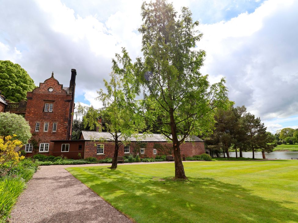 A building and trees with a path leading to a lake at South Tower Cottage Capesthorne near Macclesfield