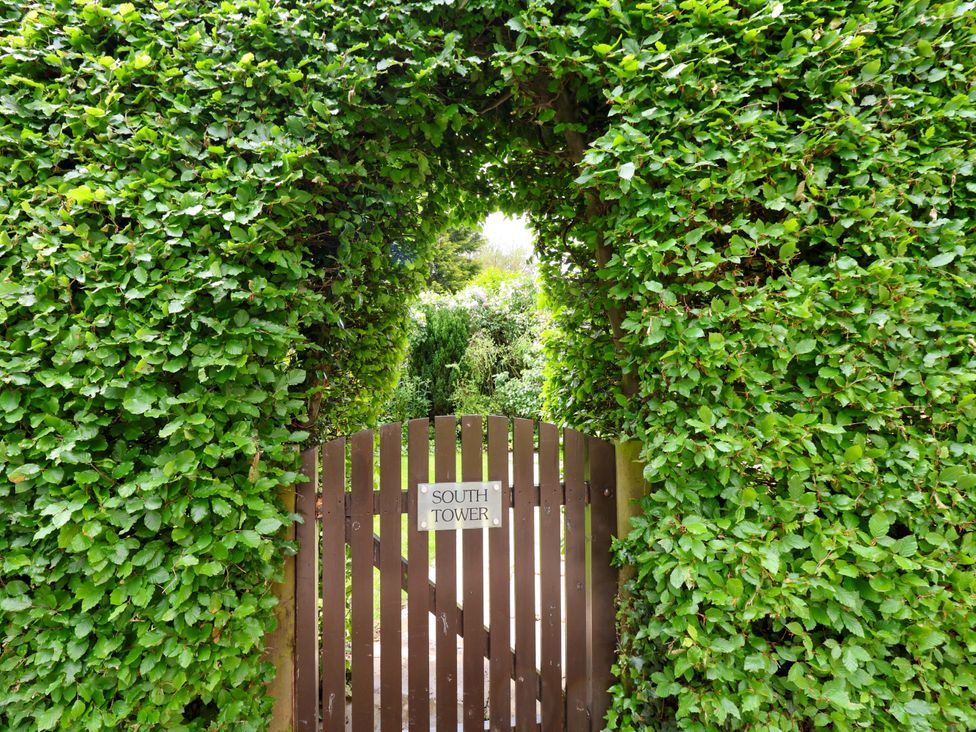 A wooden gate with a sign labeled South Tower in a garden at South Tower Cottage Capesthorne near Macclesfield