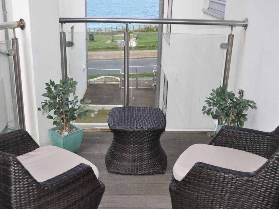 A balcony with chairs and a table overlooking the sea at 28 Zenith Porth