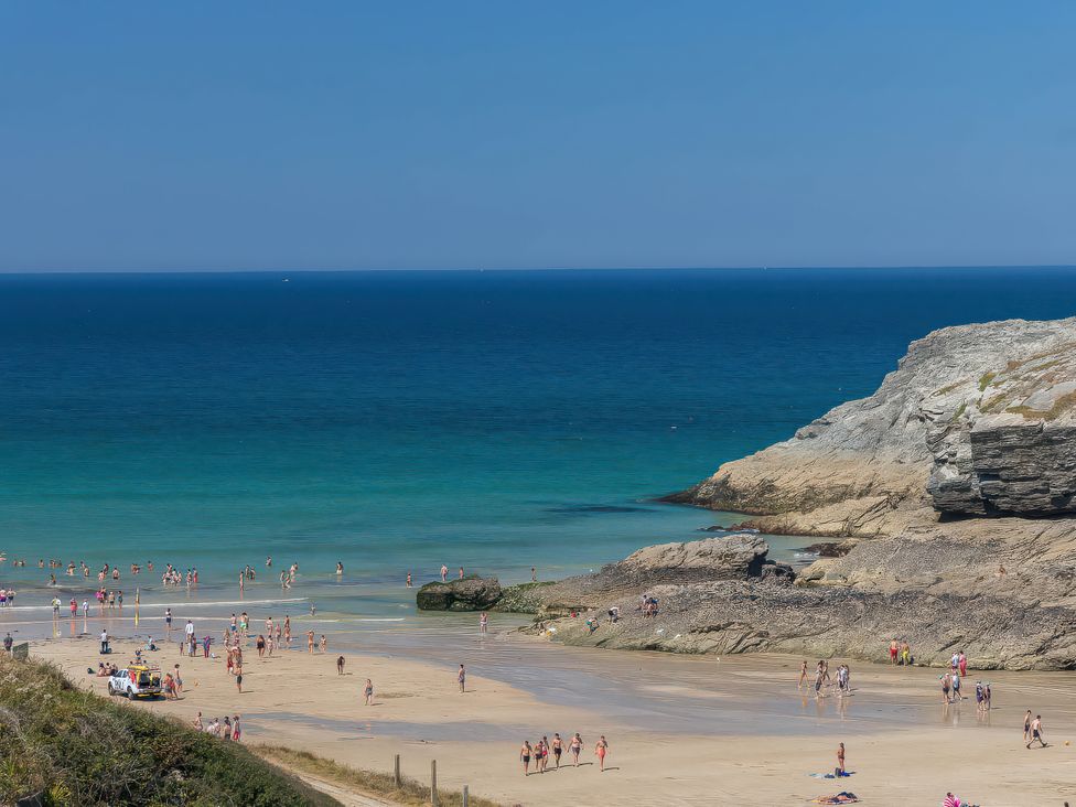 A beach with people walking and swimming near the water
