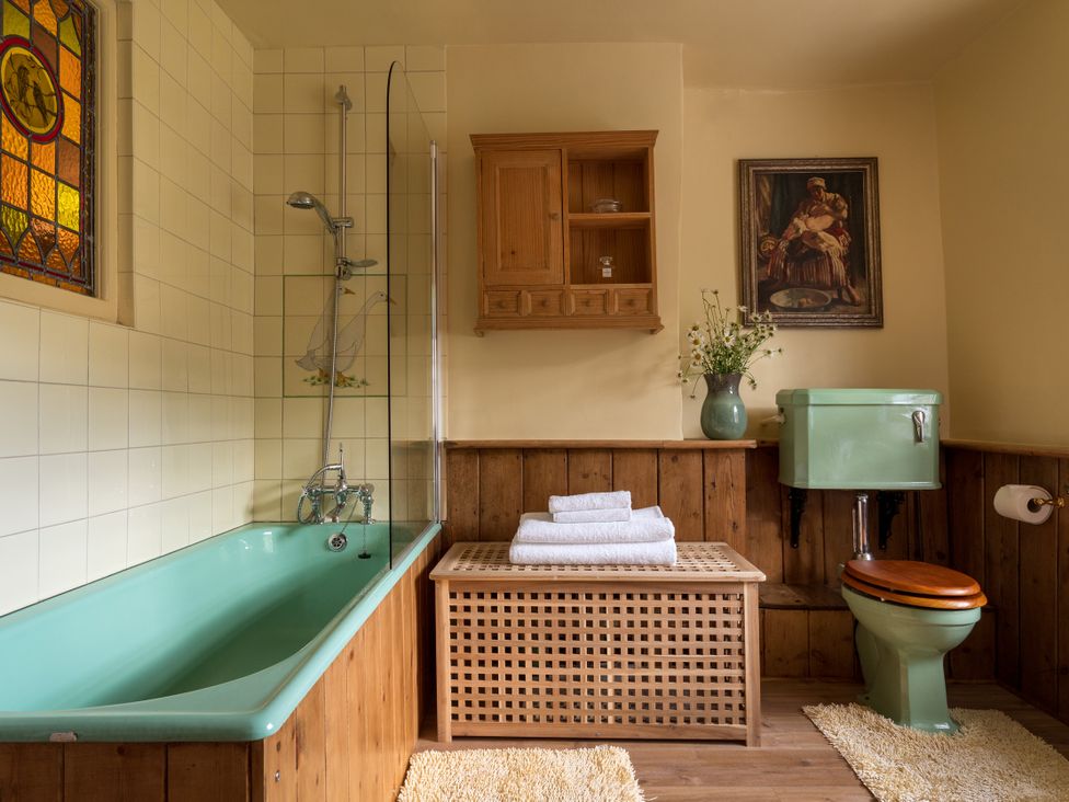 A bathroom with a tub a toilet and a storage cabinet at The Meeting House in Ashburton