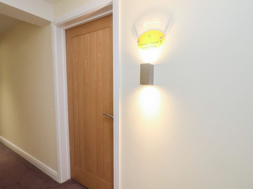A hallway with a door and wall light fixture at Premier, Transit & Lady Hilda @ Engine Shed in Whitby