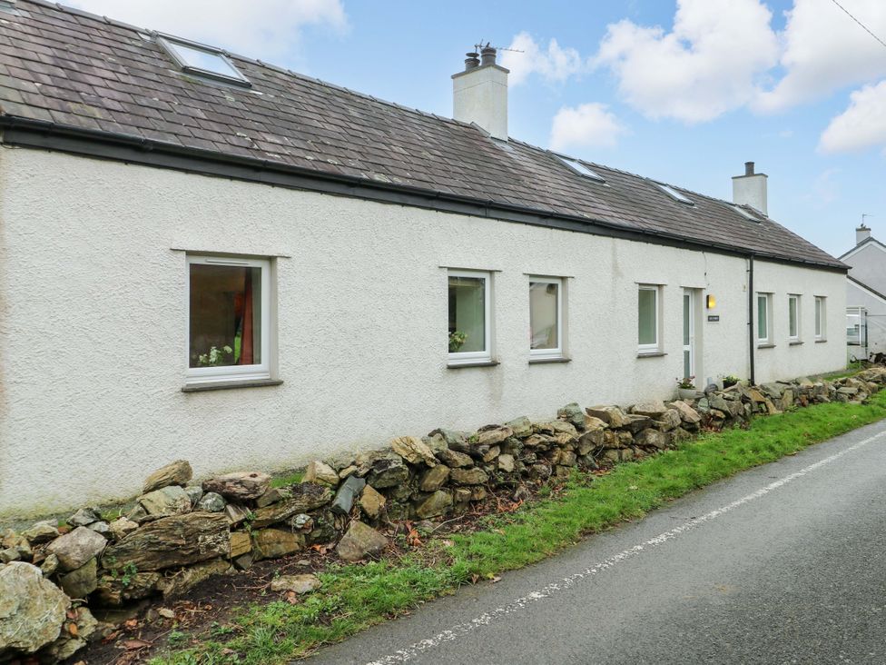 A house with windows and a door next to a stone wall at Ael Y Bryn Menai Bridge