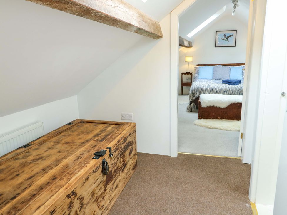 A bedroom with a wooden chest and doorway leading to another room at Ael Y Bryn Menai Bridge