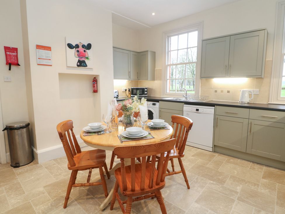 A kitchen with a round table and four chairs at South Lodge - Longford Hall Farm Holiday Cottages in Longford near Ashbourne