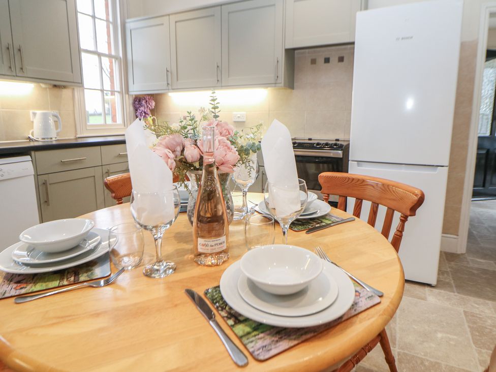 A kitchen with a dining table set for a meal at South Lodge - Longford Hall Farm Holiday Cottages in Longford near Ashbourne