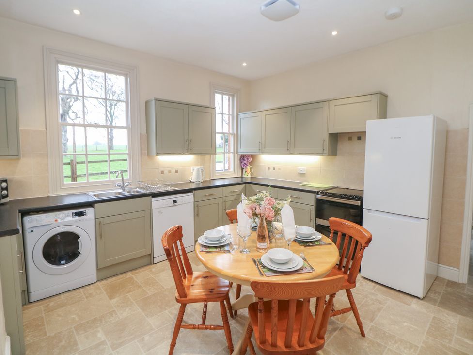 A kitchen with a dining table and chairs at South Lodge - Longford Hall Farm Holiday Cottages Longford near Ashbourne