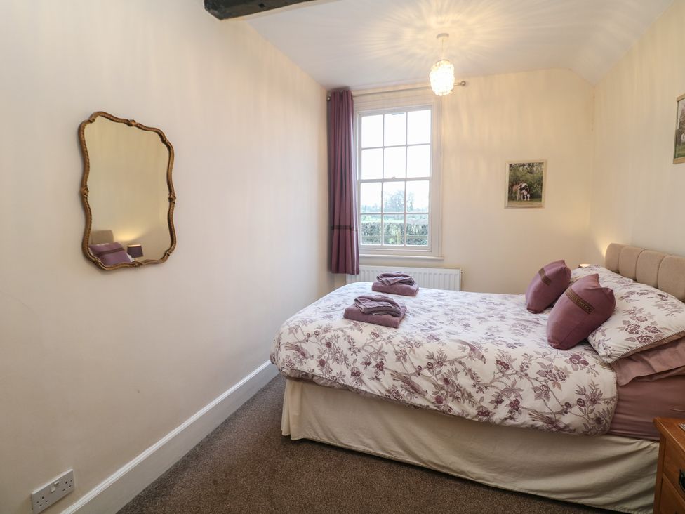 A bedroom with a bed and a mirror at South Lodge - Longford Hall Farm Holiday Cottages Longford near Ashbourne