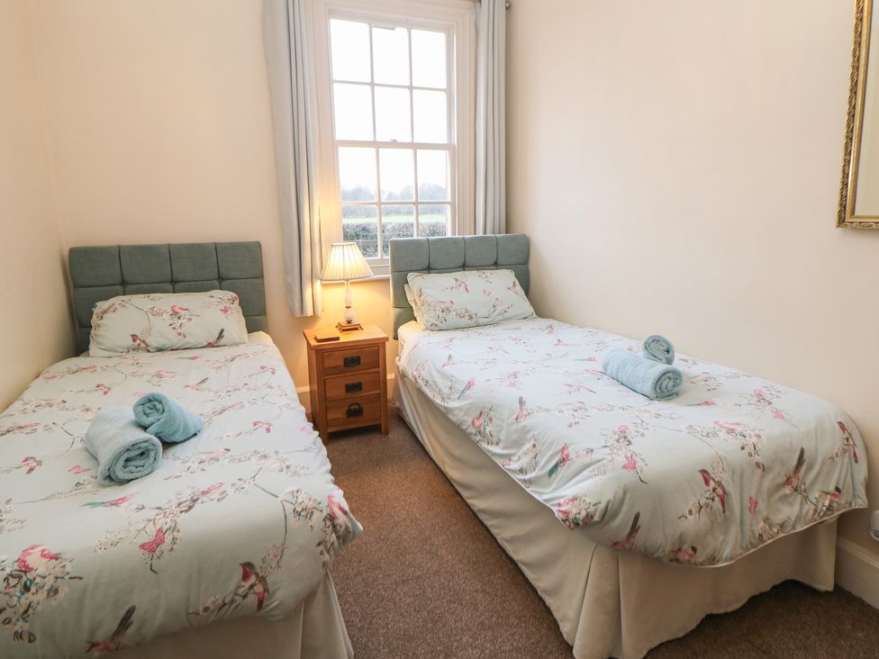 A bedroom with two single beds and a bedside lamp at South Lodge - Longford Hall Farm Holiday Cottages in Longford near Ashbourne