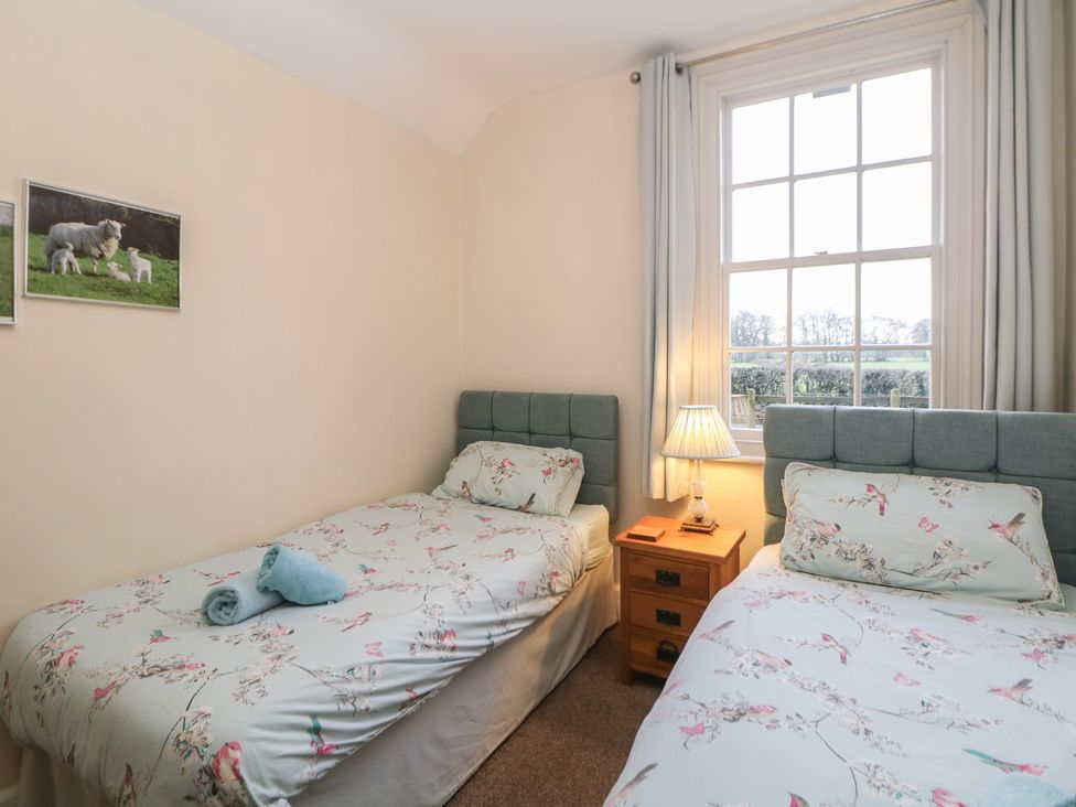 A bedroom with two single beds and a bedside table at South Lodge - Longford Hall Farm Holiday Cottages Longford near Ashbourne
