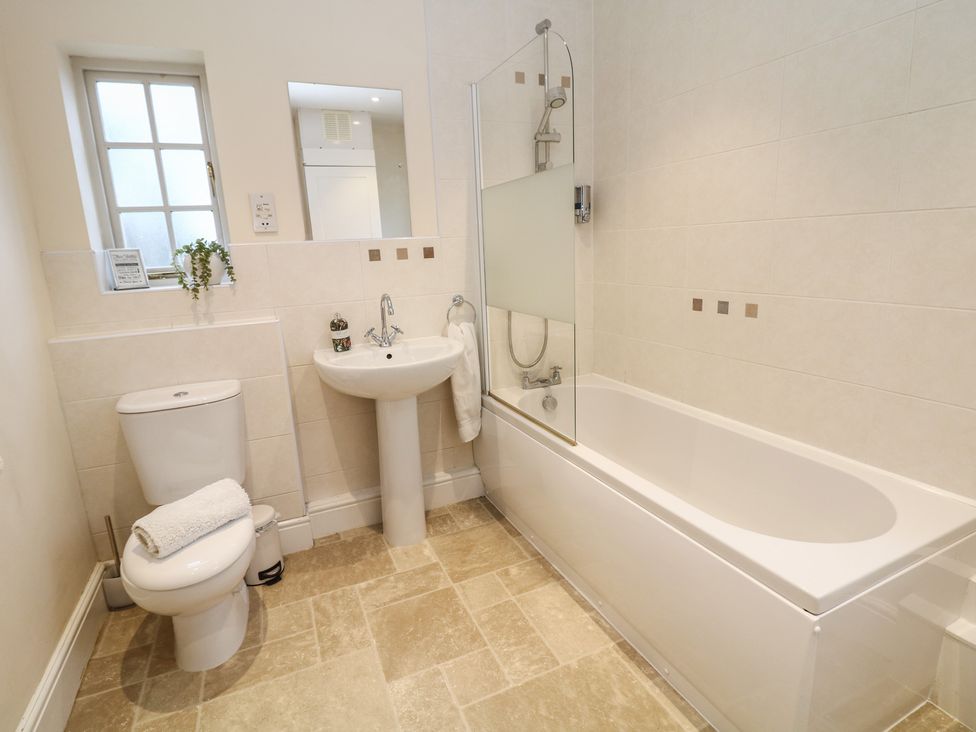 A bathroom with a sink, bathtub, toilet, and shower at South Lodge - Longford Hall Farm Holiday Cottages in Longford near Ashbourne