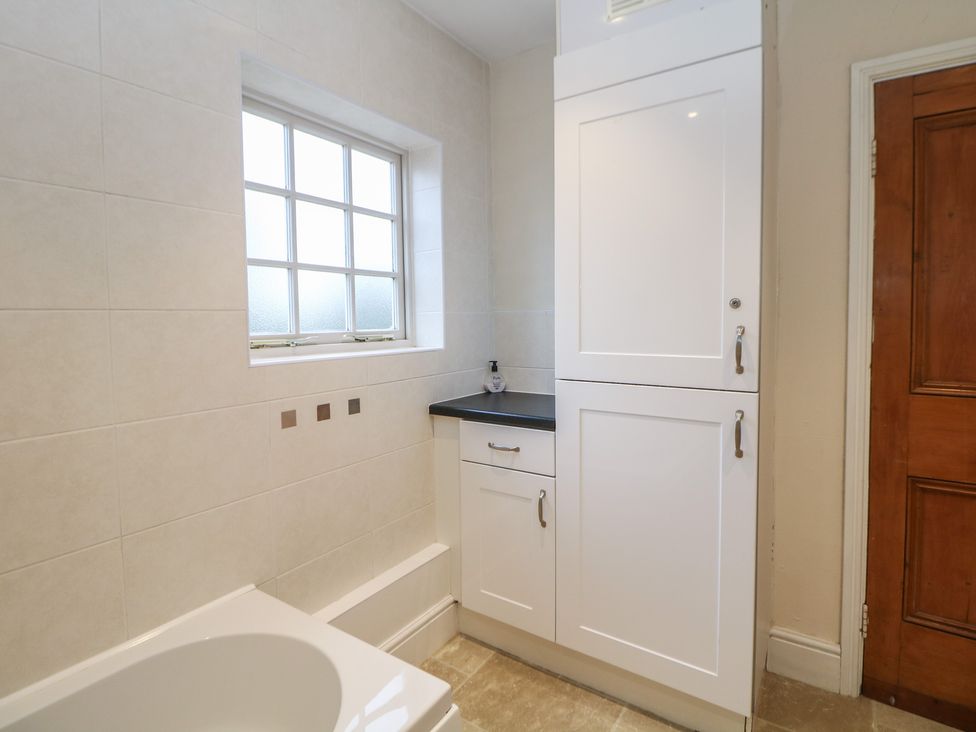 A bathroom with a bathtub, sink, and vanity unit at South Lodge - Longford Hall Farm Holiday Cottages in Longford near Ashbourne